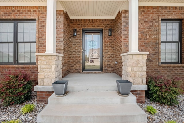 property entrance with a porch and brick siding