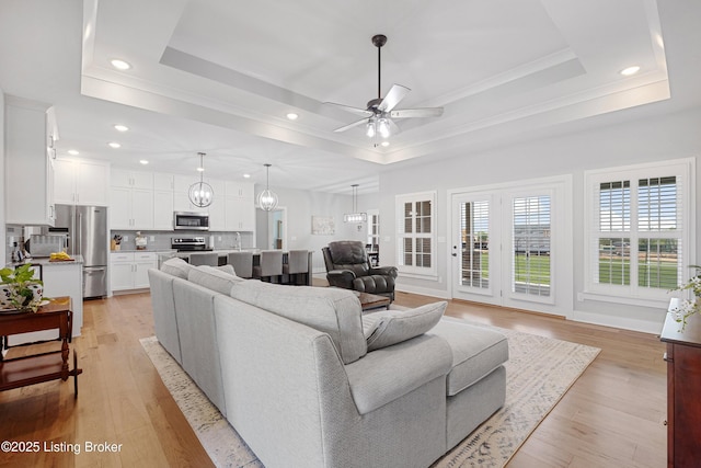 living room featuring recessed lighting, a ceiling fan, a tray ceiling, and ornamental molding