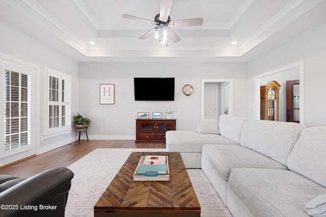 living room with a raised ceiling, recessed lighting, and wood finished floors