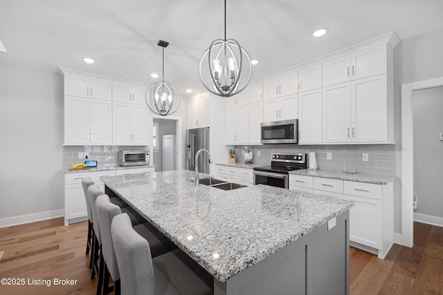 kitchen with an inviting chandelier, baseboards, stainless steel appliances, and a sink