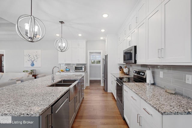 kitchen featuring a sink, a chandelier, stainless steel appliances, recessed lighting, and tasteful backsplash