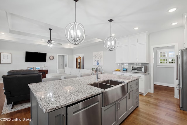 kitchen with recessed lighting, white cabinets, light stone counters, a sink, and appliances with stainless steel finishes