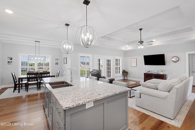 kitchen featuring crown molding, a sink, gray cabinets, baseboards, and wood finished floors