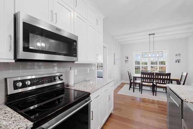 kitchen with backsplash, stainless steel appliances, white cabinets, and light wood-style floors