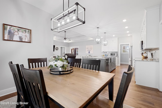 dining room with light wood-style floors, baseboards, ceiling fan with notable chandelier, and recessed lighting