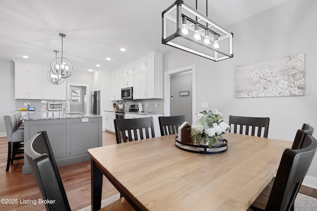 dining area featuring light wood finished floors, recessed lighting, and a chandelier