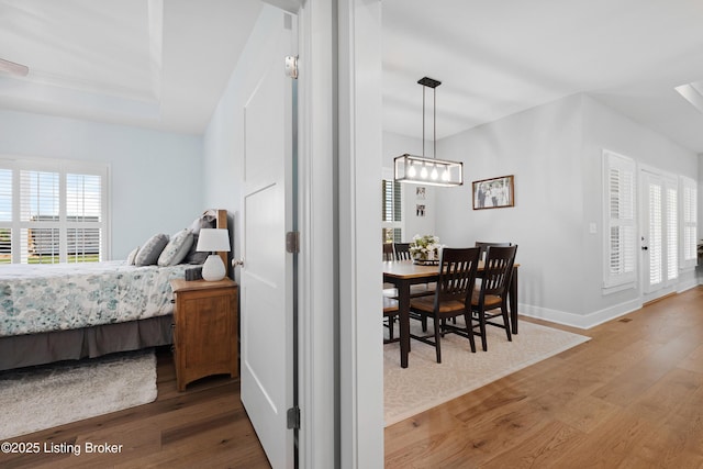 bedroom with an inviting chandelier, baseboards, and wood finished floors