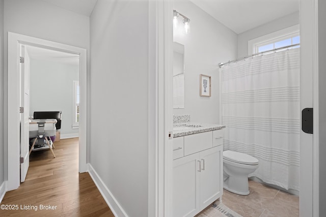 bathroom with toilet, baseboards, wood finished floors, and vanity