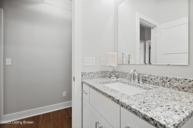bathroom with baseboards, wood finished floors, and vanity