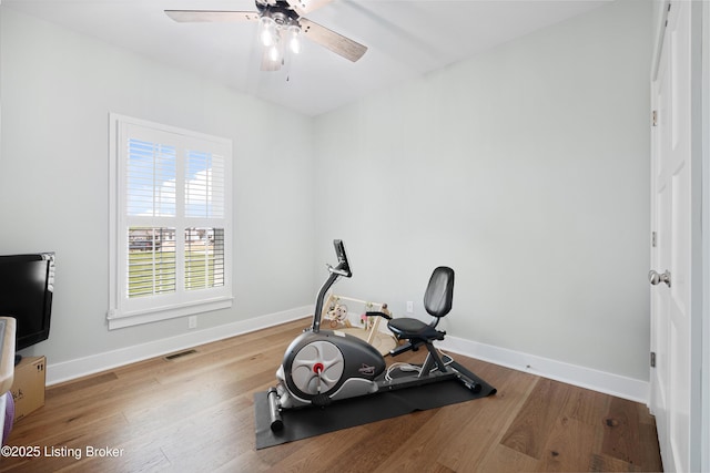 workout area with baseboards, ceiling fan, wood finished floors, and visible vents