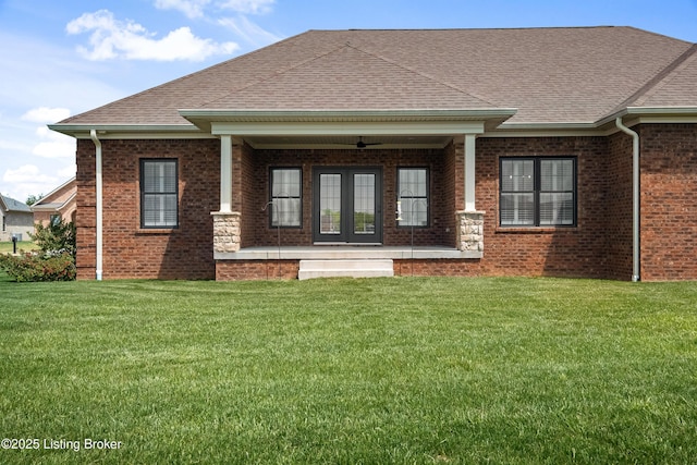 back of house with roof with shingles, ceiling fan, a yard, and brick siding