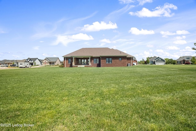 back of house with a lawn and brick siding