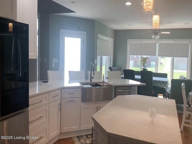 kitchen with a ceiling fan, open floor plan, light countertops, white cabinetry, and a sink