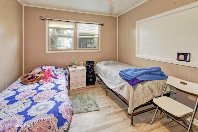 bedroom with ornamental molding and wood finished floors