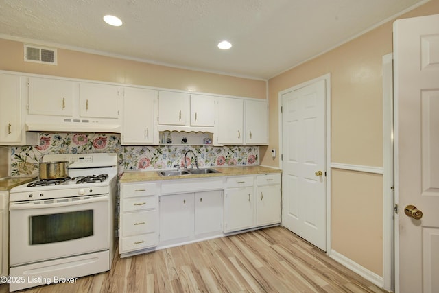 kitchen featuring visible vents, white gas range, under cabinet range hood, a sink, and light wood-style flooring