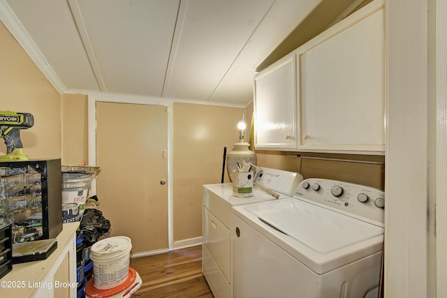 clothes washing area with washing machine and clothes dryer, wood finished floors, cabinet space, baseboards, and ornamental molding