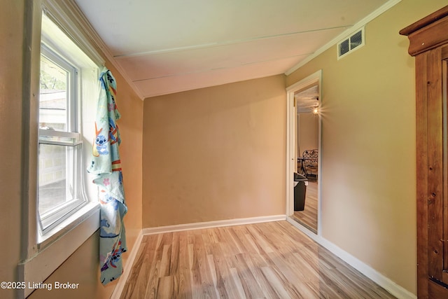 empty room with baseboards, ornamental molding, light wood-type flooring, and visible vents