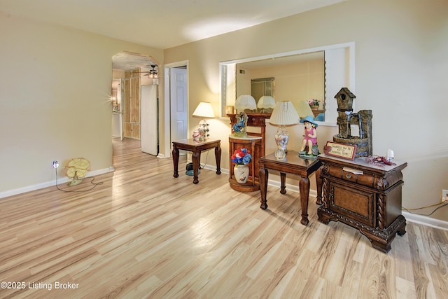 hallway with arched walkways, baseboards, and wood finished floors