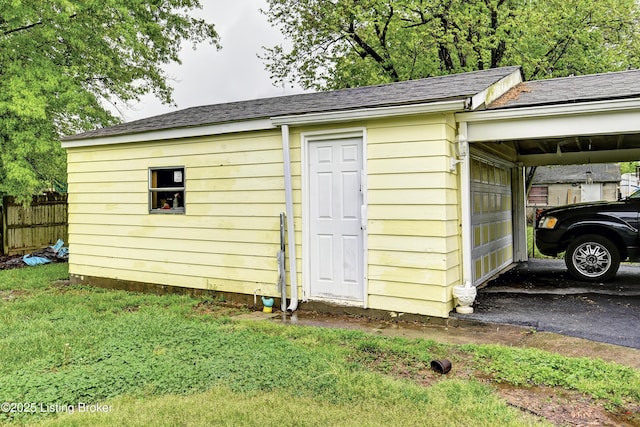 view of outbuilding with fence, an outbuilding, and a carport
