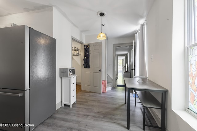 kitchen with freestanding refrigerator, pendant lighting, plenty of natural light, and wood finished floors