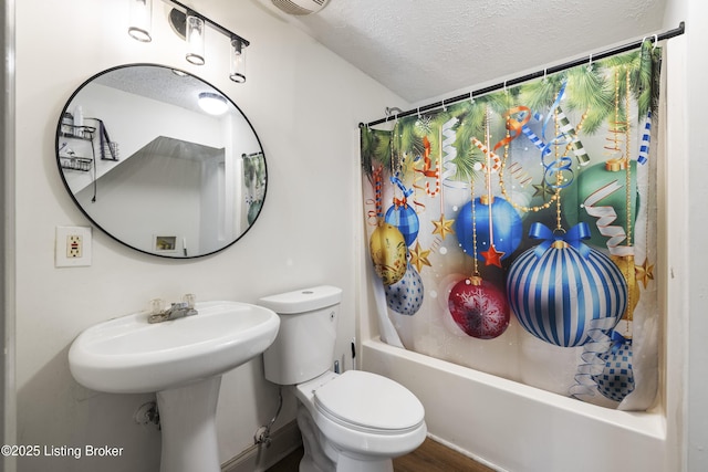 bathroom featuring toilet, a textured ceiling, wood finished floors, and shower / bath combo with shower curtain