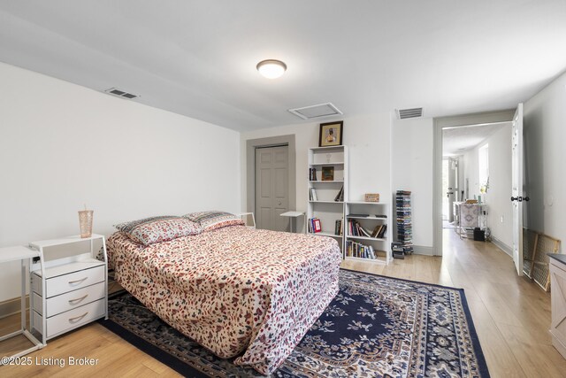 bedroom with visible vents, attic access, and light wood-type flooring