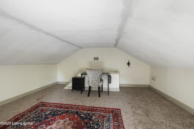 carpeted office space with a textured ceiling, vaulted ceiling, baseboards, and visible vents