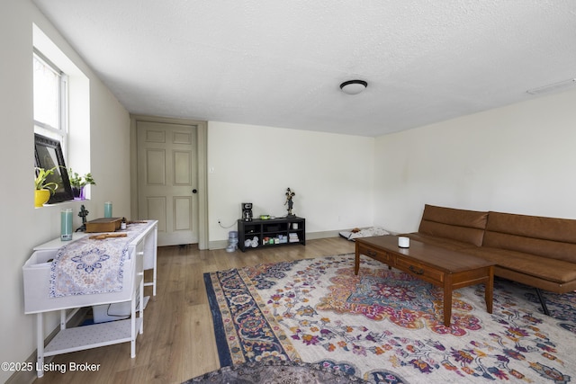 living room featuring baseboards, light wood-type flooring, a textured ceiling, and visible vents