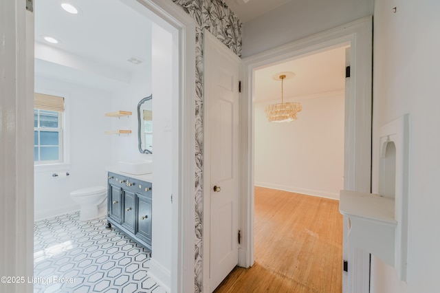 hallway featuring a sink, recessed lighting, a chandelier, light wood-style flooring, and baseboards