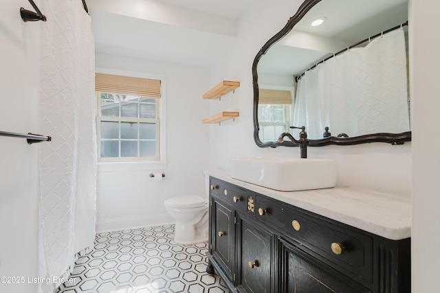 full bath with toilet, baseboards, vanity, and a healthy amount of sunlight