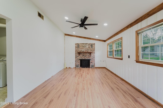 unfurnished living room featuring wood finished floors, a ceiling fan, a fireplace, visible vents, and washer / dryer