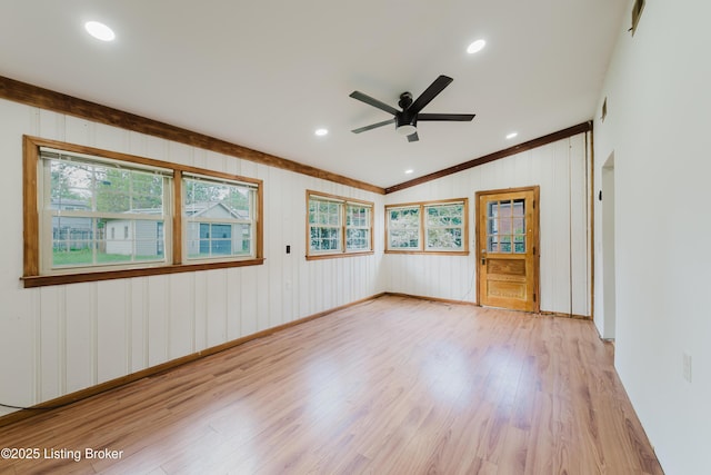 unfurnished room featuring vaulted ceiling, crown molding, light wood-style flooring, a ceiling fan, and baseboards