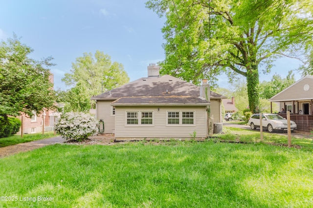rear view of property with cooling unit, roof with shingles, and a chimney