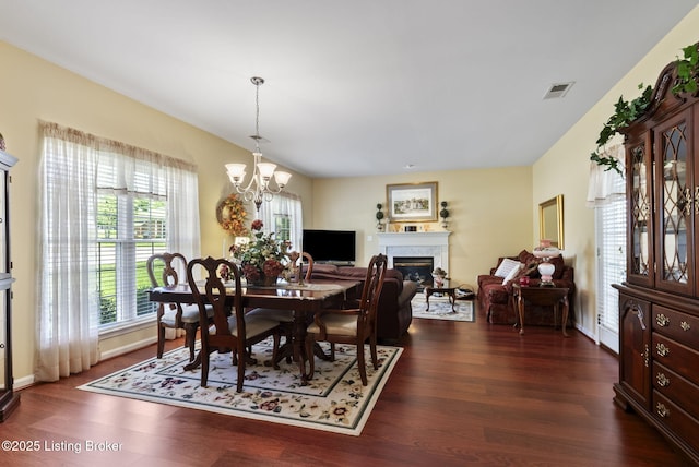 dining space with a fireplace, a notable chandelier, visible vents, and dark wood-type flooring