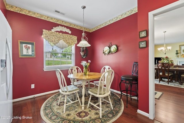 dining room featuring baseboards, a notable chandelier, visible vents, and wood finished floors