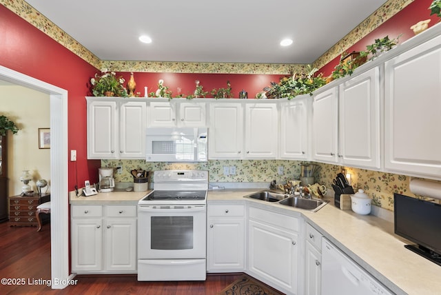 kitchen with a sink, light countertops, dark wood-style flooring, and white appliances