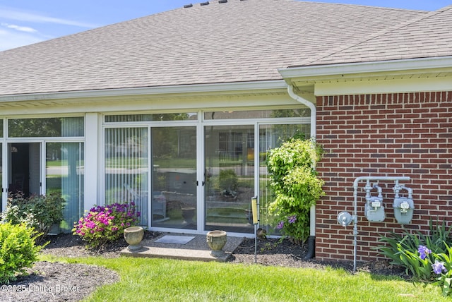 entrance to property with brick siding and a shingled roof