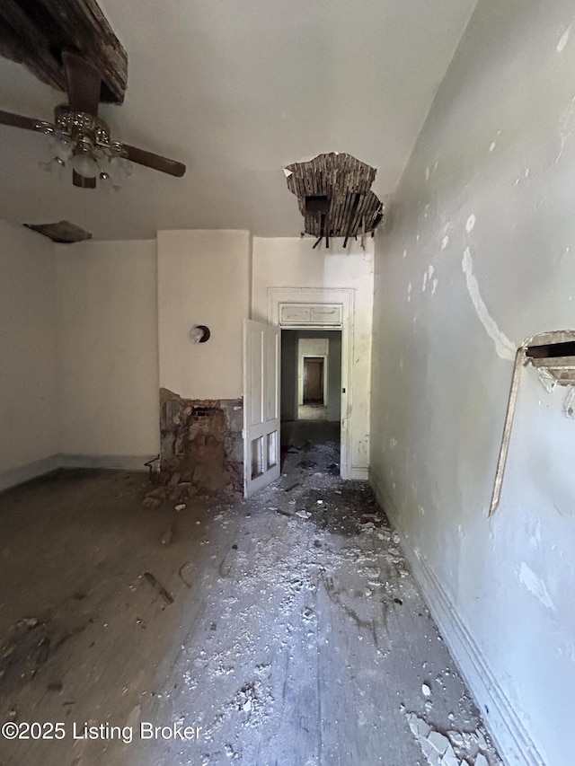 unfurnished living room with a ceiling fan and baseboards
