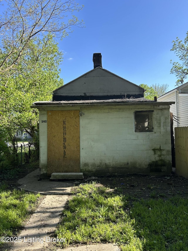 rear view of property featuring fence and concrete block siding