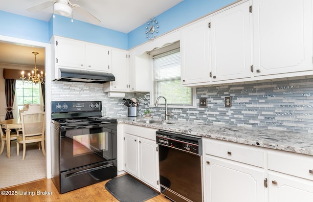 kitchen with white cabinets, a sink, light wood-style floors, under cabinet range hood, and black appliances