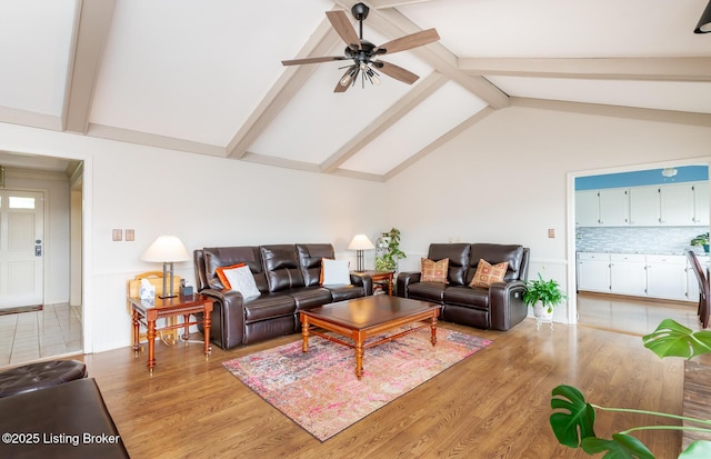 living room featuring light wood-style floors, wainscoting, a ceiling fan, and lofted ceiling with beams