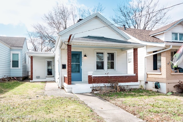shotgun-style home featuring covered porch, a shingled roof, and a front yard