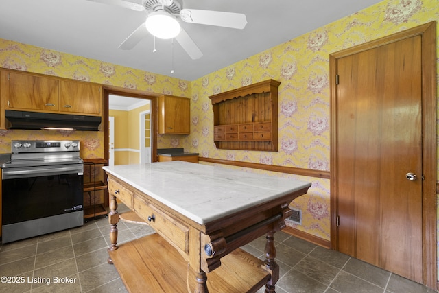 2224 Wynnewood Cir, Louisville, KY 40222 - kitchen with under cabinet range hood, stainless steel electric range, wallpapered walls, brown cabinetry, and dark tile patterned flooring