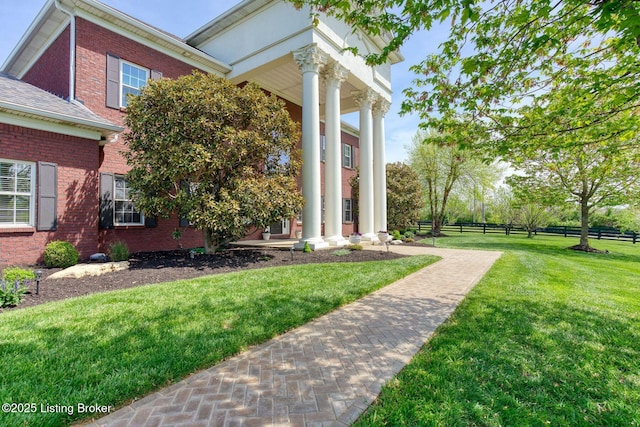 view of side of property with a yard, brick siding, and fence