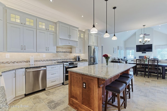 kitchen with a center island, tasteful backsplash, stainless steel appliances, and stone tile flooring
