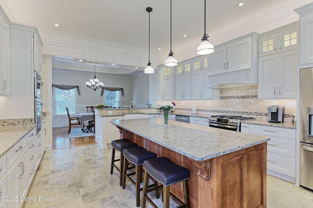 kitchen with crown molding, tasteful backsplash, a peninsula, a chandelier, and stainless steel appliances