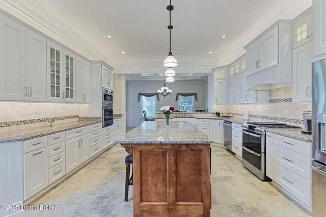 kitchen featuring crown molding, appliances with stainless steel finishes, backsplash, and stone tile flooring