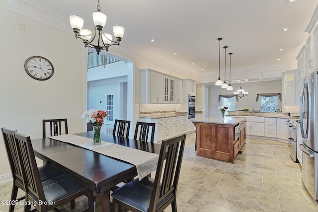 dining room with stone tile floors, a chandelier, and ornamental molding