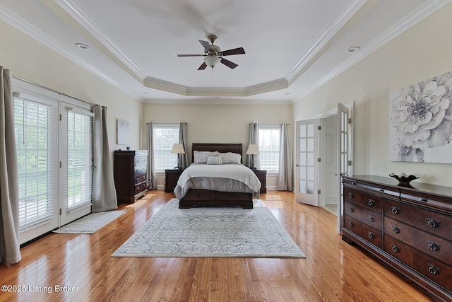 bedroom with crown molding, access to outside, light wood-style flooring, and a raised ceiling