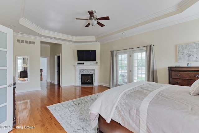 bedroom featuring crown molding, a tray ceiling, and a fireplace